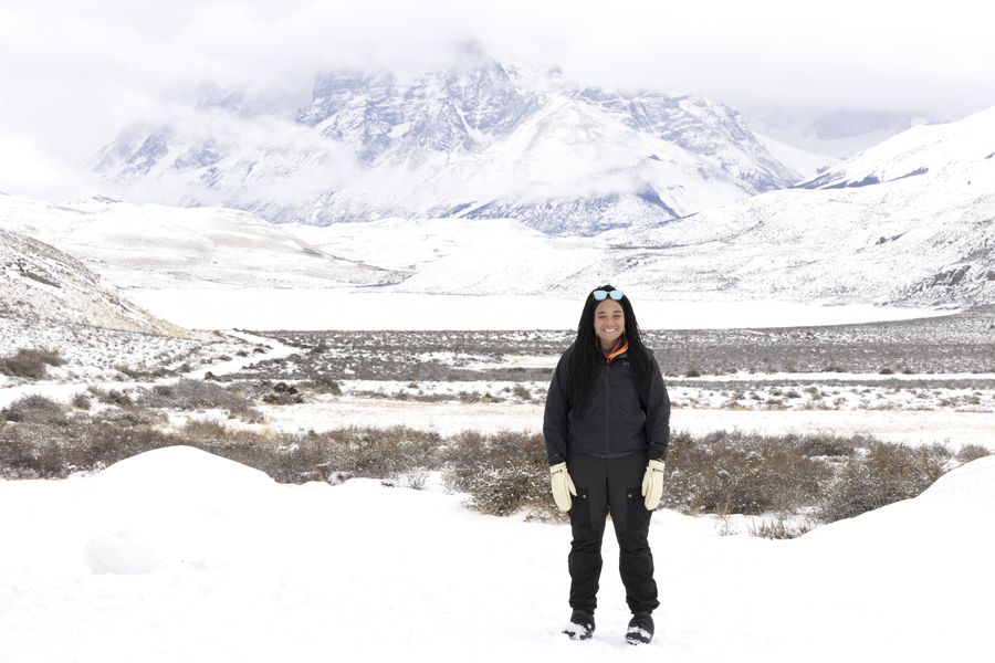 Taylor standing in deep snow below jagged, snow-covered mountains