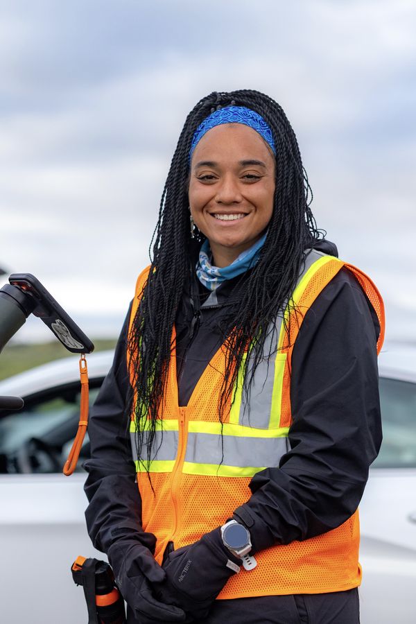 Taylor smiling in the field, in a hi-vis vest and blue headband